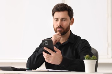 Photo of Handsome man using smartphone at table in office