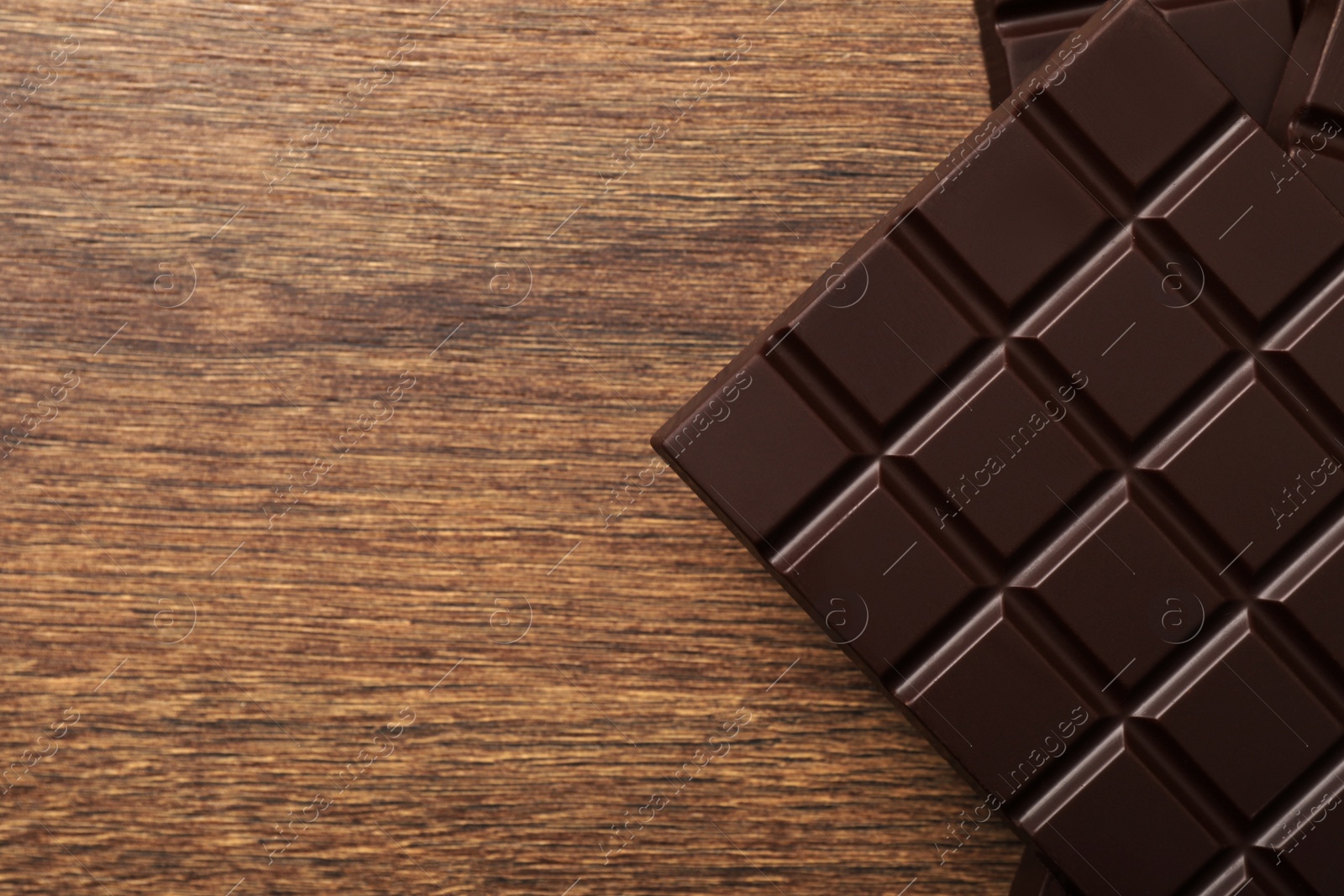 Photo of Tasty chocolate bars on wooden table, flat lay. Space for text