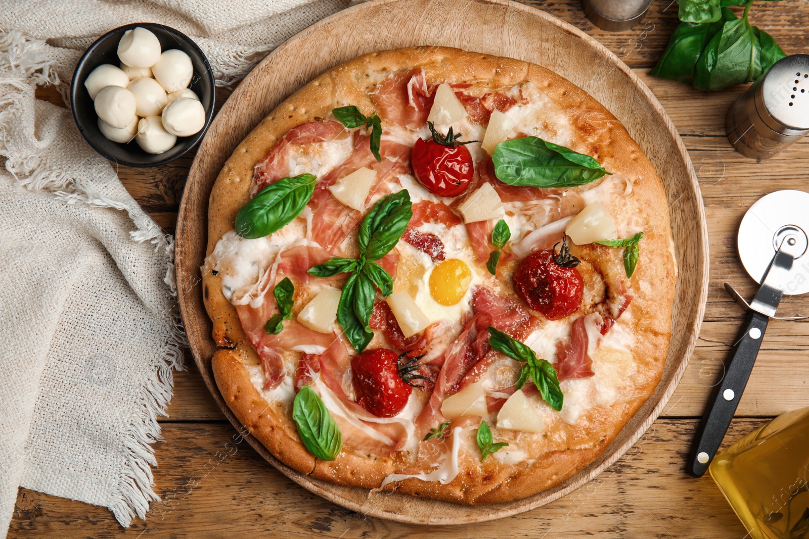 Photo of Pita pizza with prosciutto, pineapple, grilled tomatoes and egg on wooden table, flat lay