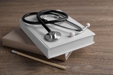 Photo of Student textbooks, pencil and stethoscope on wooden table. Medical education