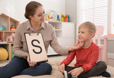 Speech therapist working with little boy in office