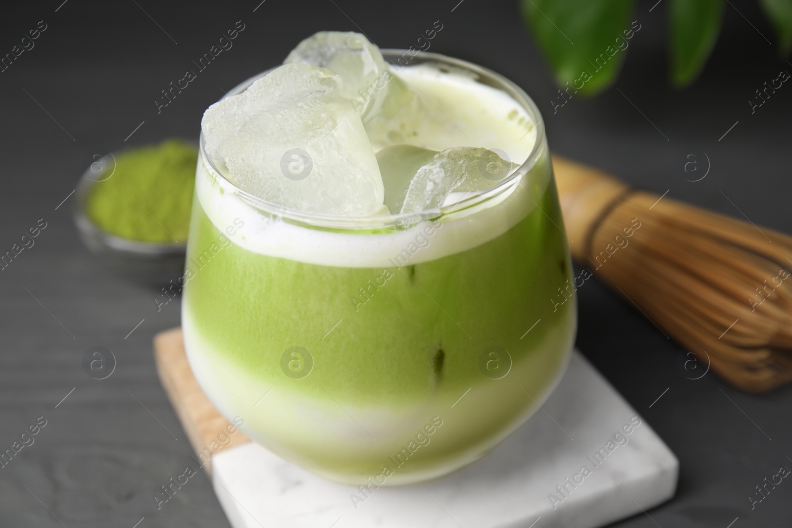 Photo of Glass of tasty iced matcha latte on grey wooden table, closeup