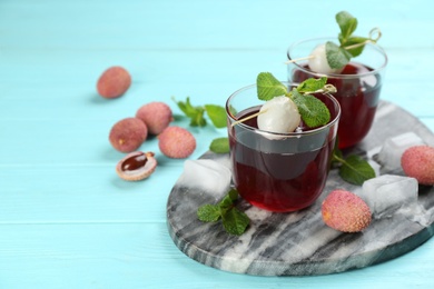 Photo of Lychee cocktail on cyan wooden table, space for text