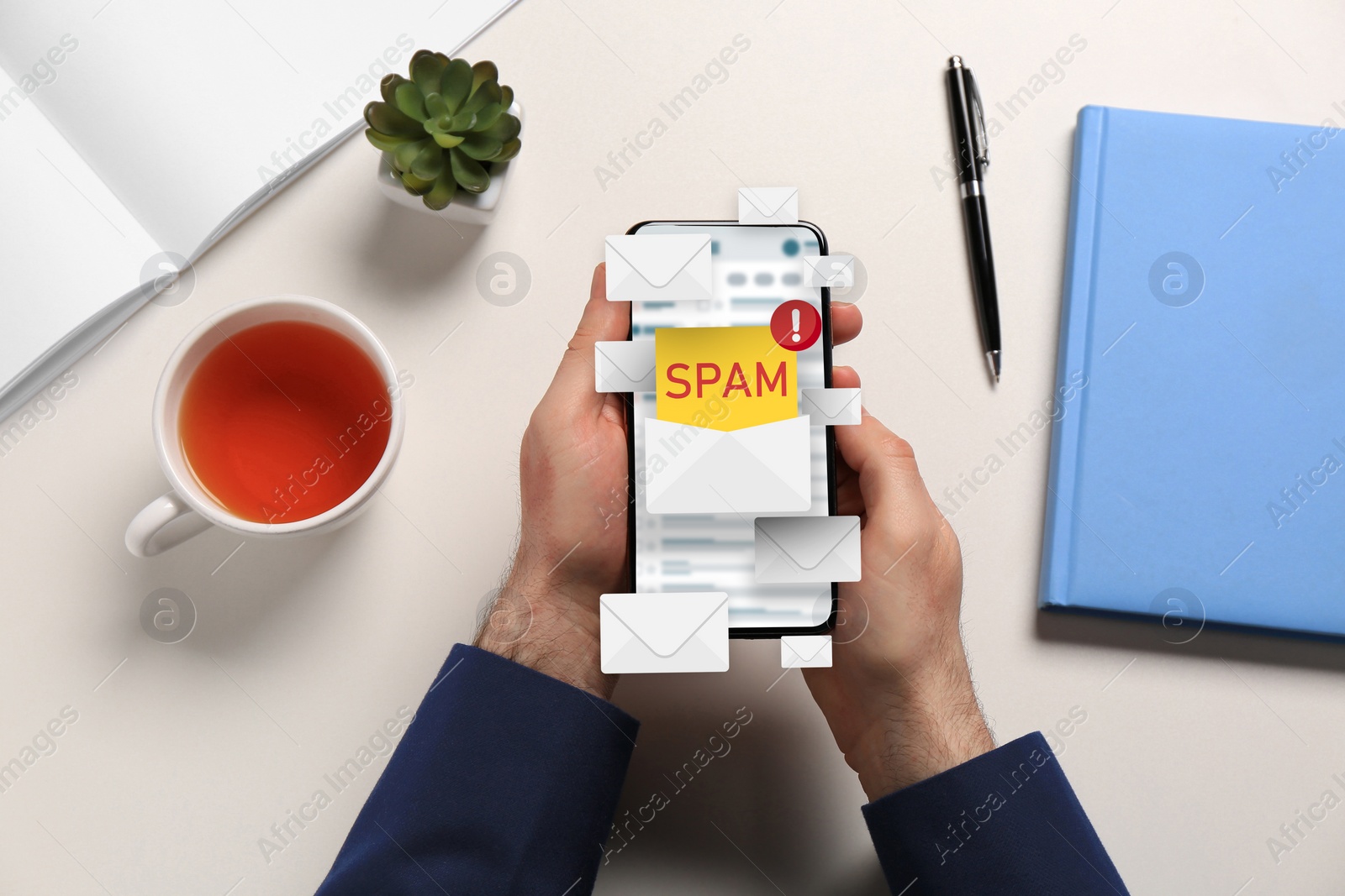 Image of Spam warning message, envelope illustrations popping out of device display. Man using email software on smartphone at table, top view