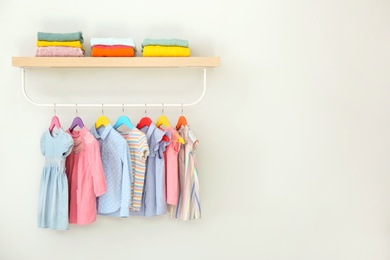 Rack with different clothes on light background. Space for text