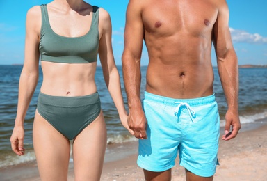 Photo of Woman in bikini and her boyfriend on beach, closeup. Lovely couple