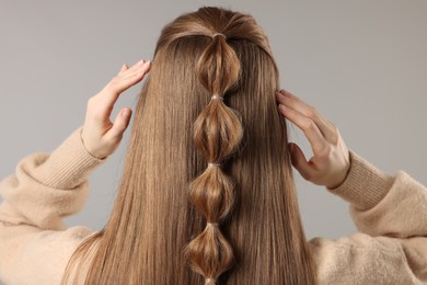 Woman with braided hair on grey background, back view