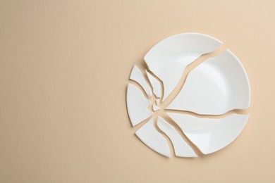 Photo of Pieces of broken ceramic plate on beige background, flat lay. Space for text