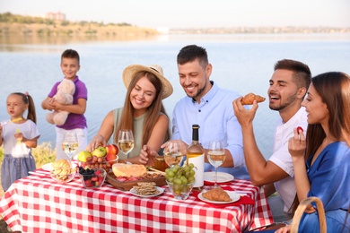 Photo of Happy families with little children having picnic at riverside