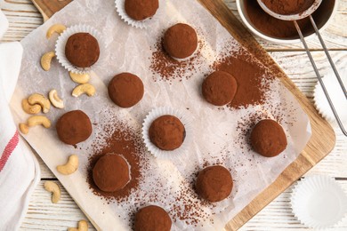 Photo of Delicious chocolate truffles with cocoa powder and nuts on white wooden table, flat lay