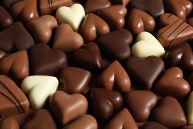 Photo of Beautiful heart shaped chocolate candies on brown background