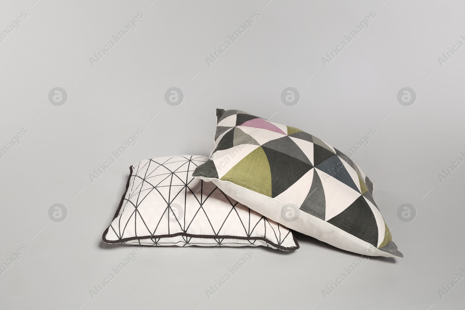 Photo of Pile of stylish decorative pillows on light background