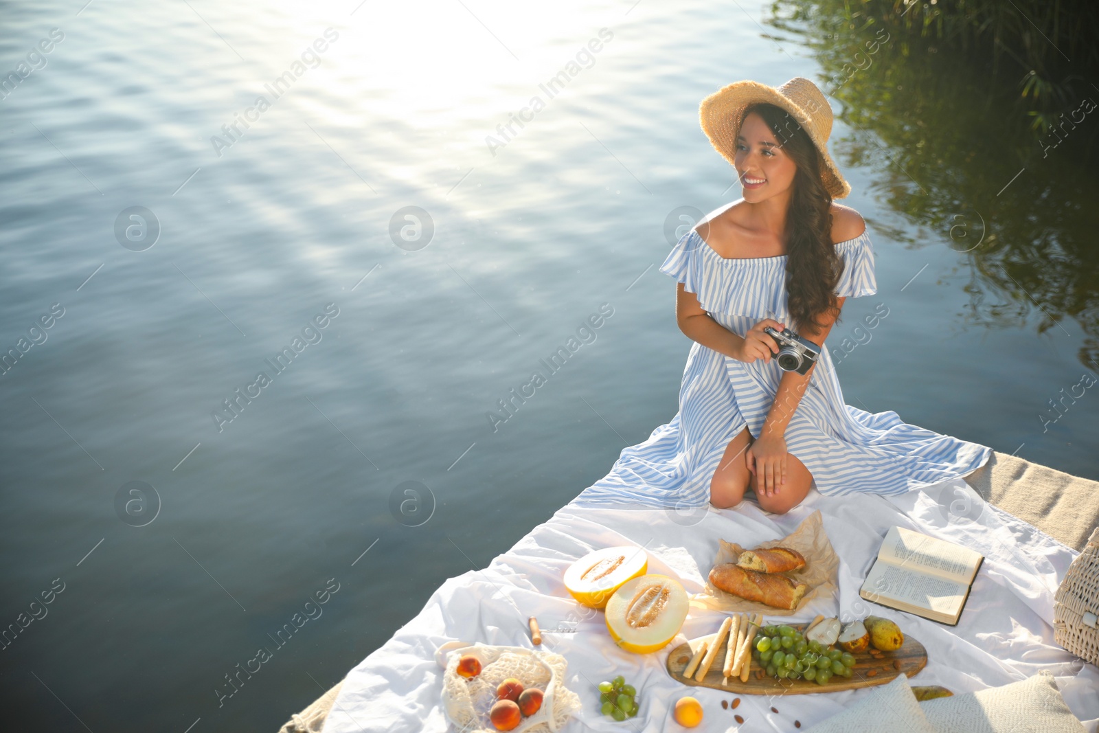 Photo of Young woman with camera on pier at picnic