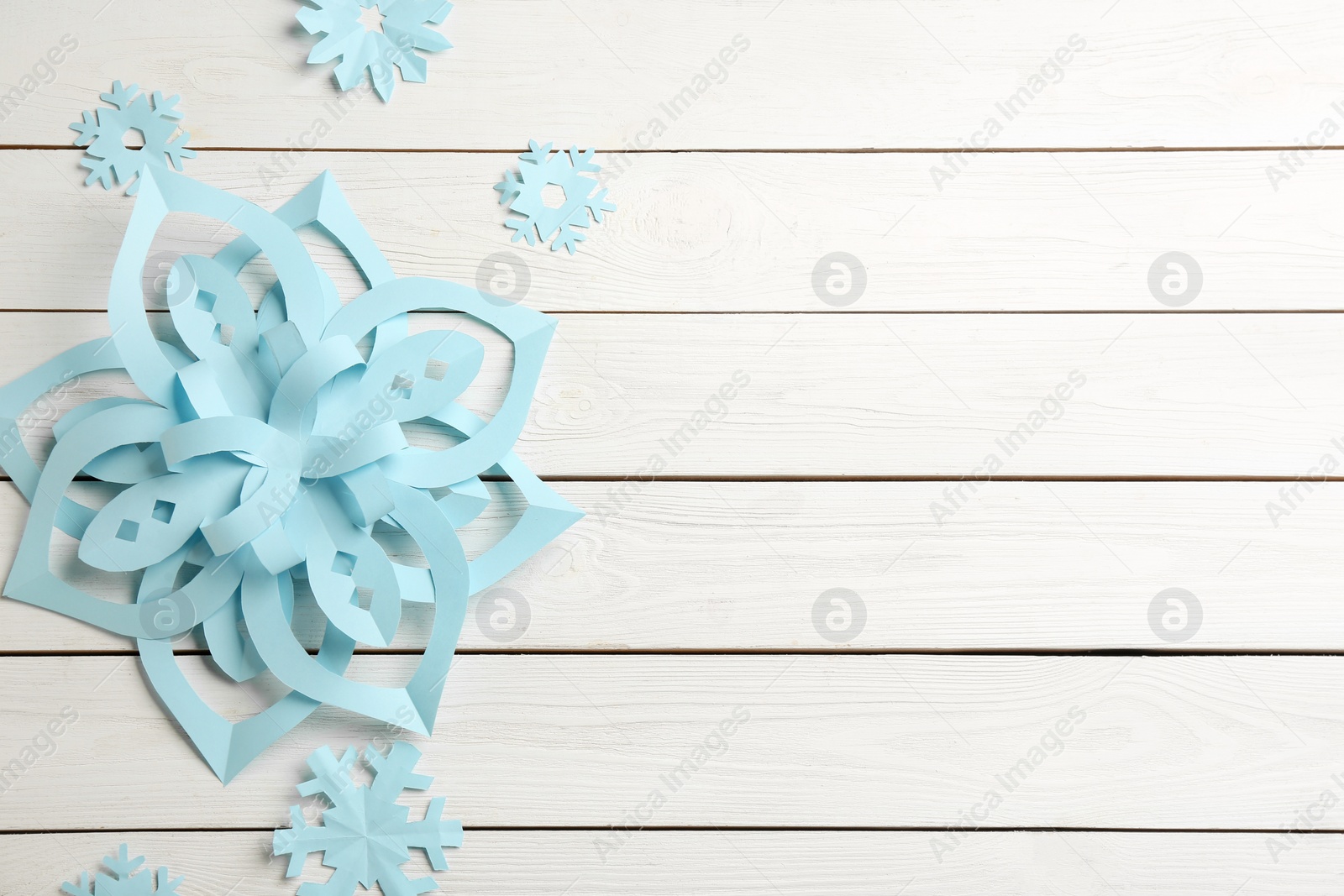 Photo of Many paper snowflakes on white wooden background, flat lay. Space for text