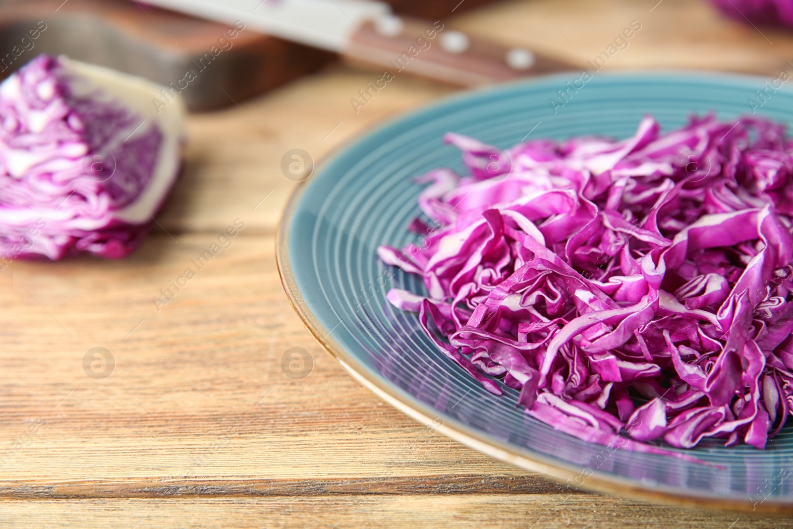 Photo of Shredded red cabbage on wooden table, closeup