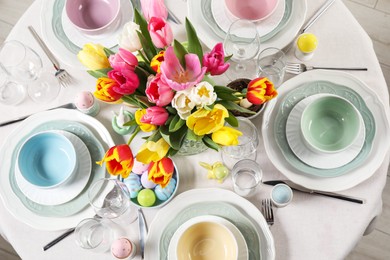 Festive Easter table setting with beautiful flowers and painted eggs, top view