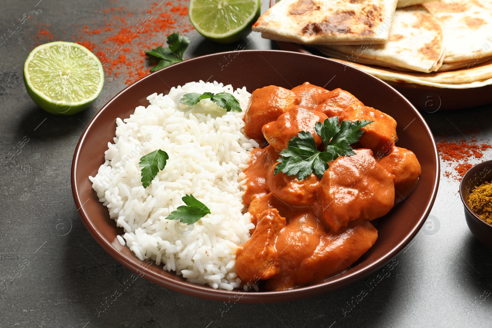 Photo of Delicious butter chicken with rice served on grey table