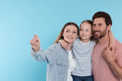 Happy family on light blue background, space for text