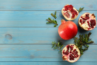 Photo of Flat lay composition with ripe pomegranates on light blue wooden table. Space for text