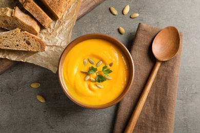 Photo of Flat lay composition with delicious pumpkin cream soup in bowl on gray background