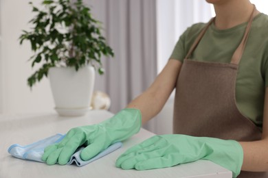 Woman with microfiber cloth cleaning white table in room, closeup