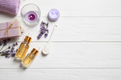 Flat lay composition with essential oil and lavender flowers on white wooden background. Space for text