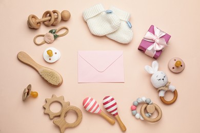 Photo of Envelope for baby shower and accessories on light pink background, flat lay