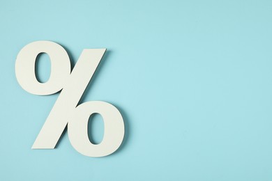 Photo of White percent sign on light blue background, top view. Space for text