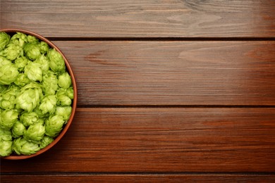Photo of Bowl with fresh green hops on wooden table, top view. Space for text