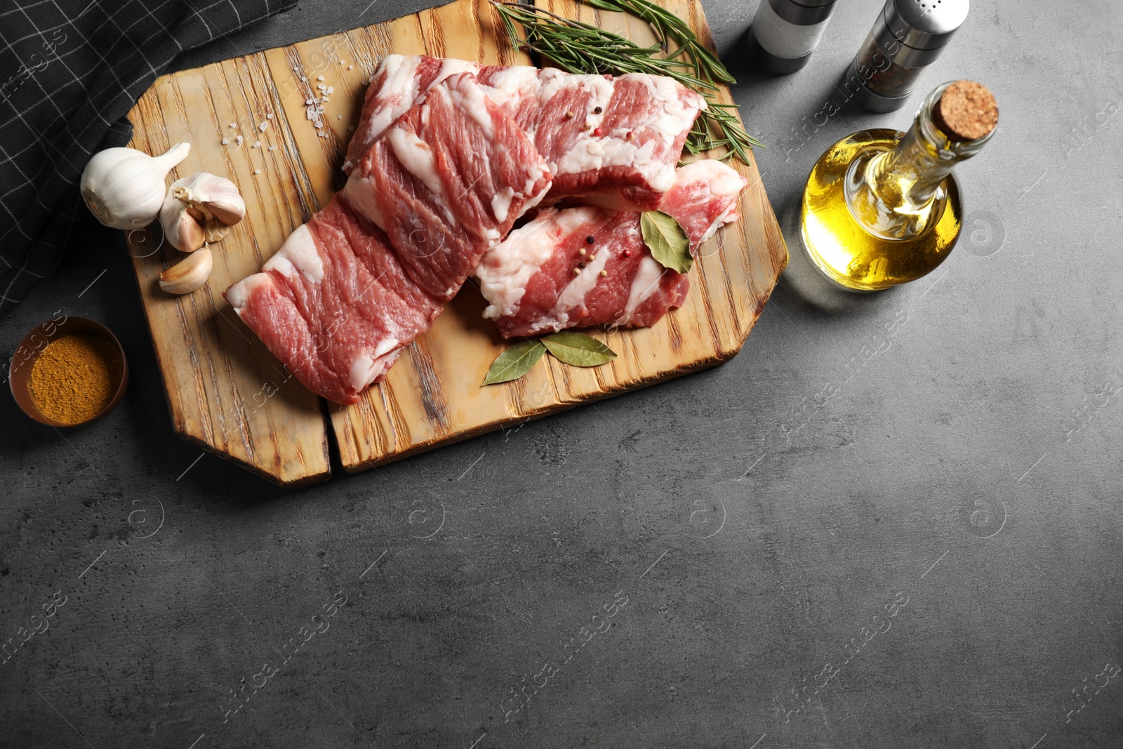 Photo of Raw ribs with herbs and spices on grey table, flat lay