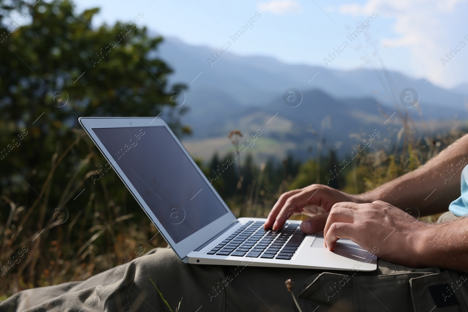 Photo of Man working with laptop outdoors on sunny day, closeup