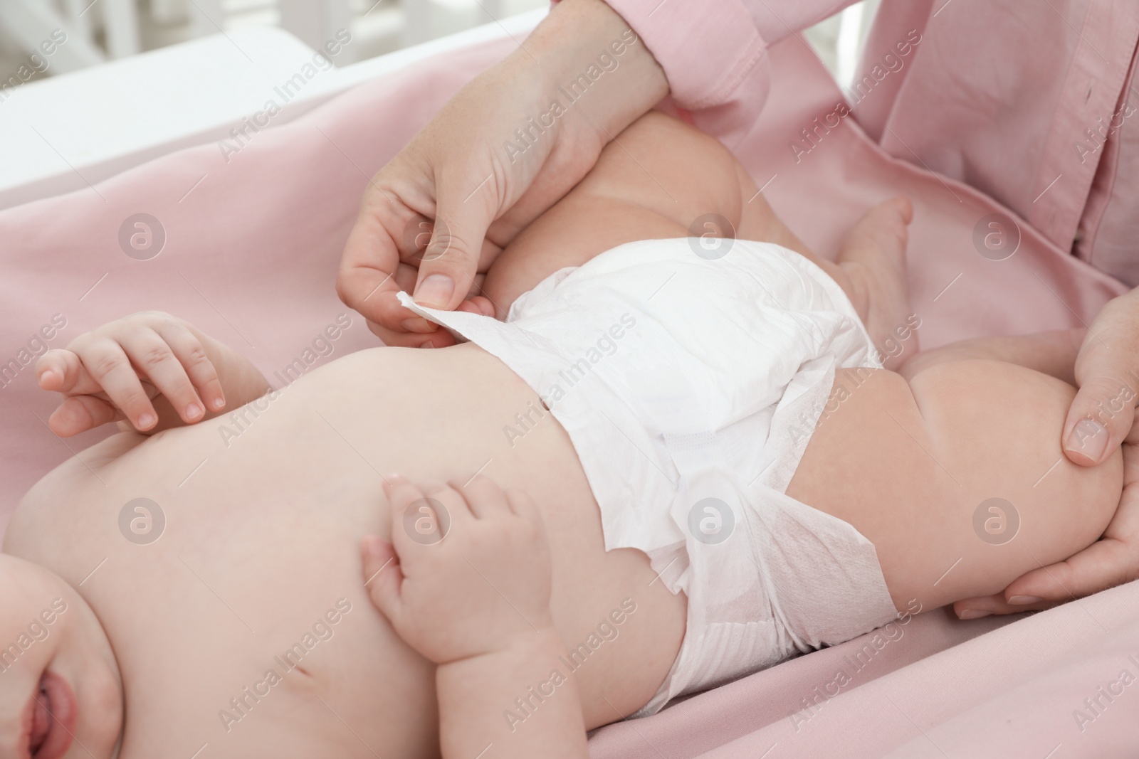 Photo of Mother changing baby's diaper on table at home, closeup