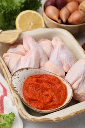 Fresh marinade, raw chicken and other products on light table, closeup