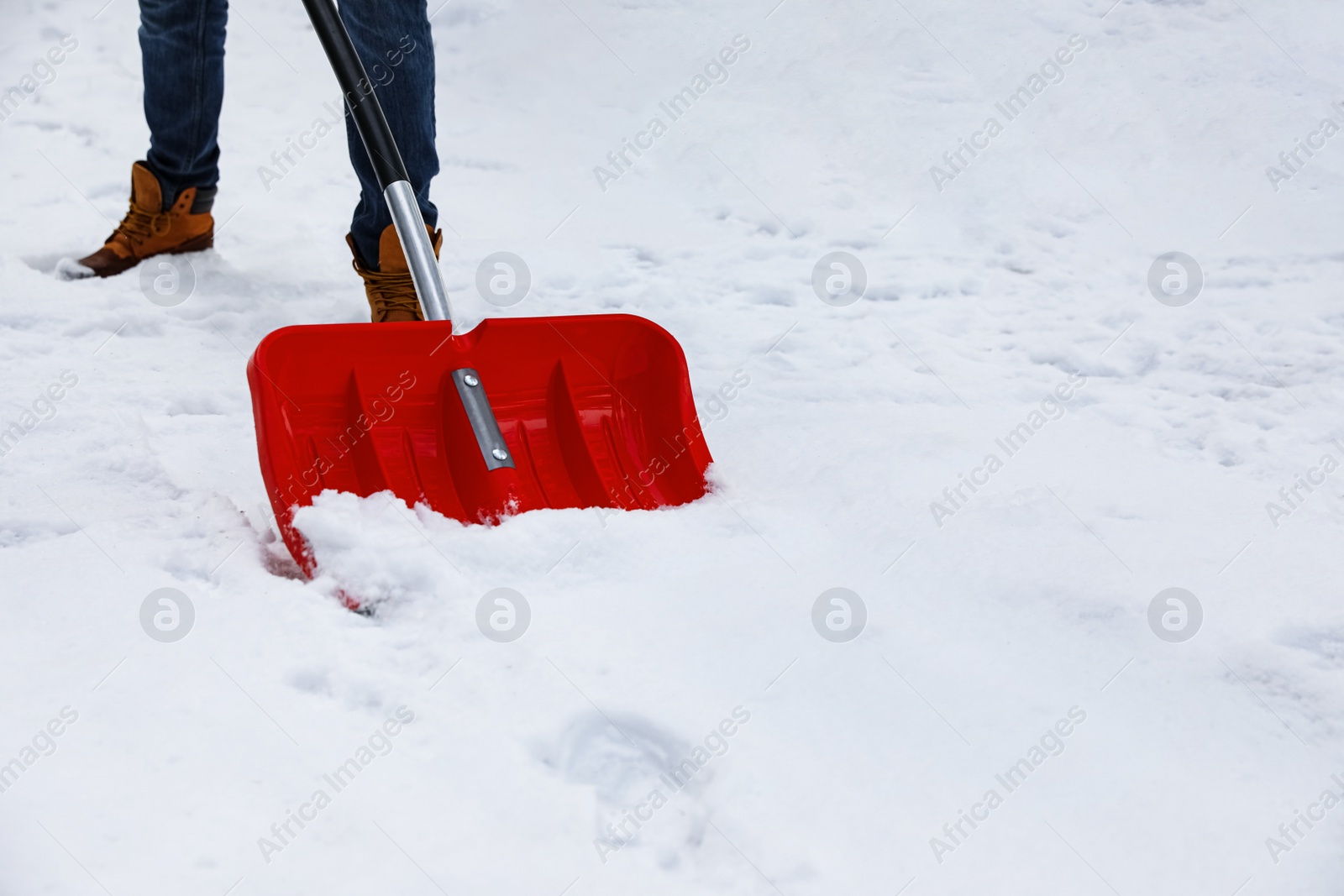 Photo of Man removing snow with shovel outdoors on winter day, closeup