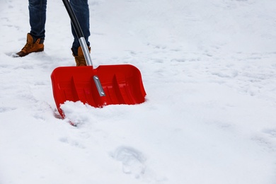 Photo of Man removing snow with shovel outdoors on winter day, closeup