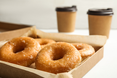 Delicious donuts in box on white table