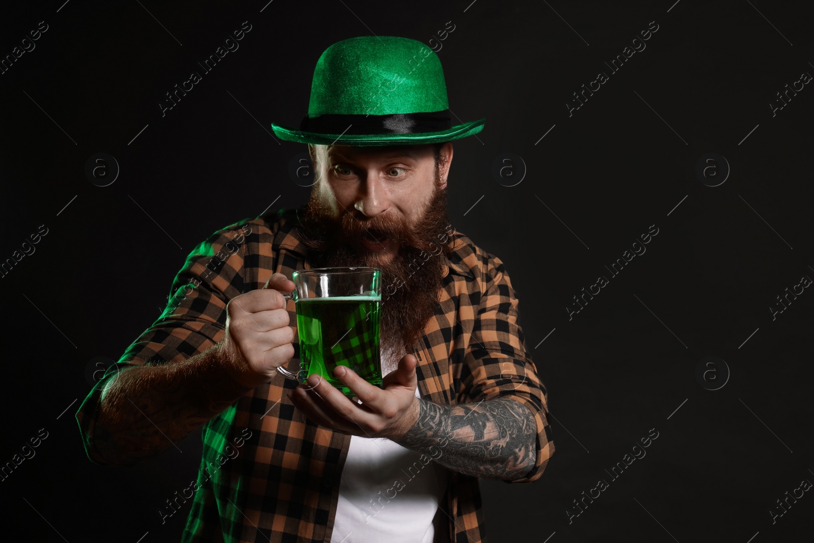 Photo of Bearded man with green beer on black background. St. Patrick's Day celebration