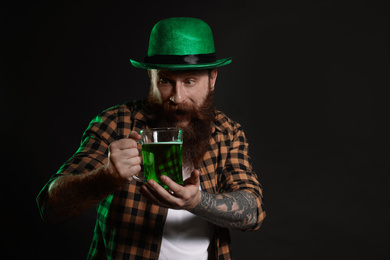 Bearded man with green beer on black background. St. Patrick's Day celebration