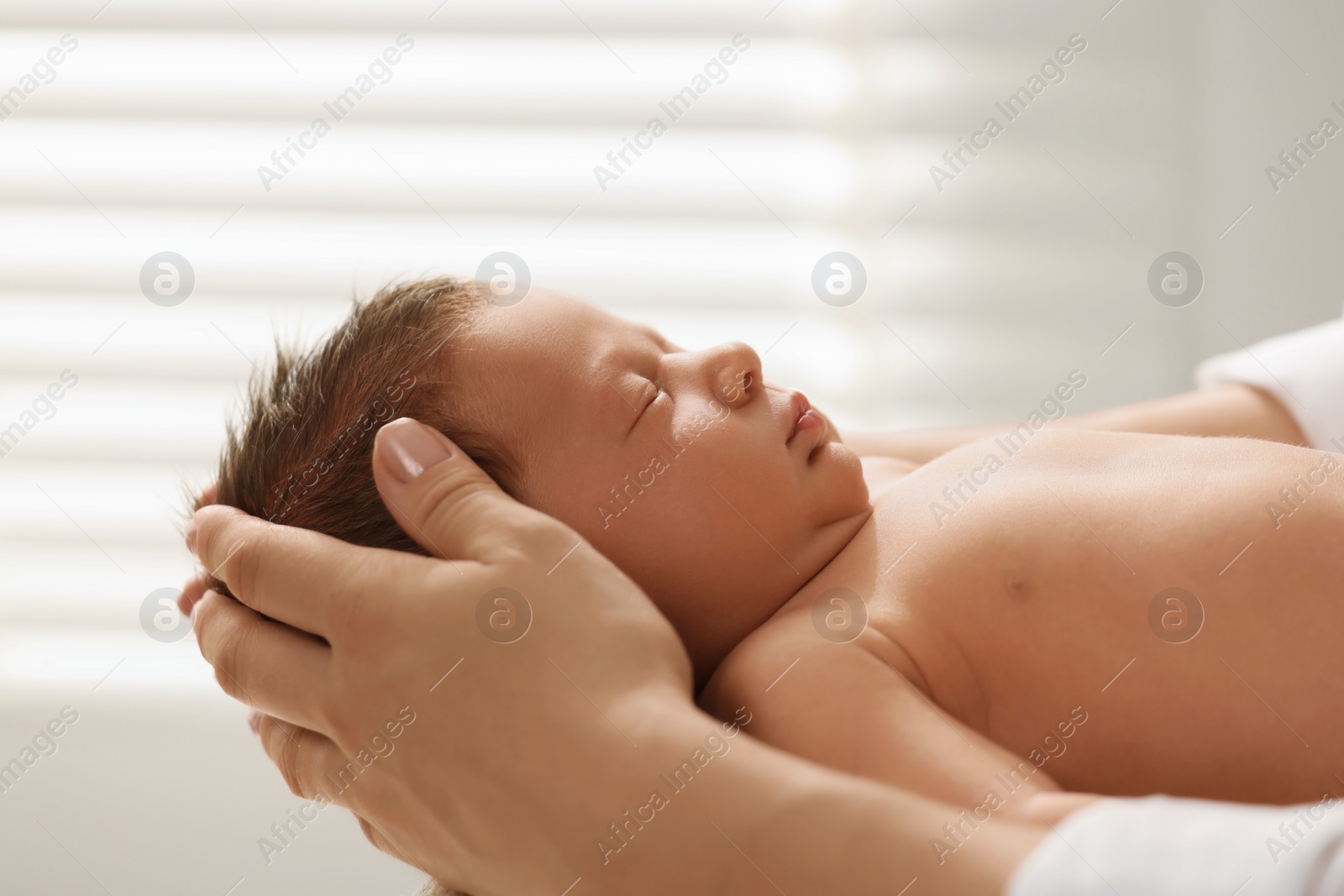 Photo of Mother holding her cute newborn baby indoors, closeup