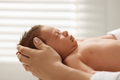 Mother holding her cute newborn baby indoors, closeup