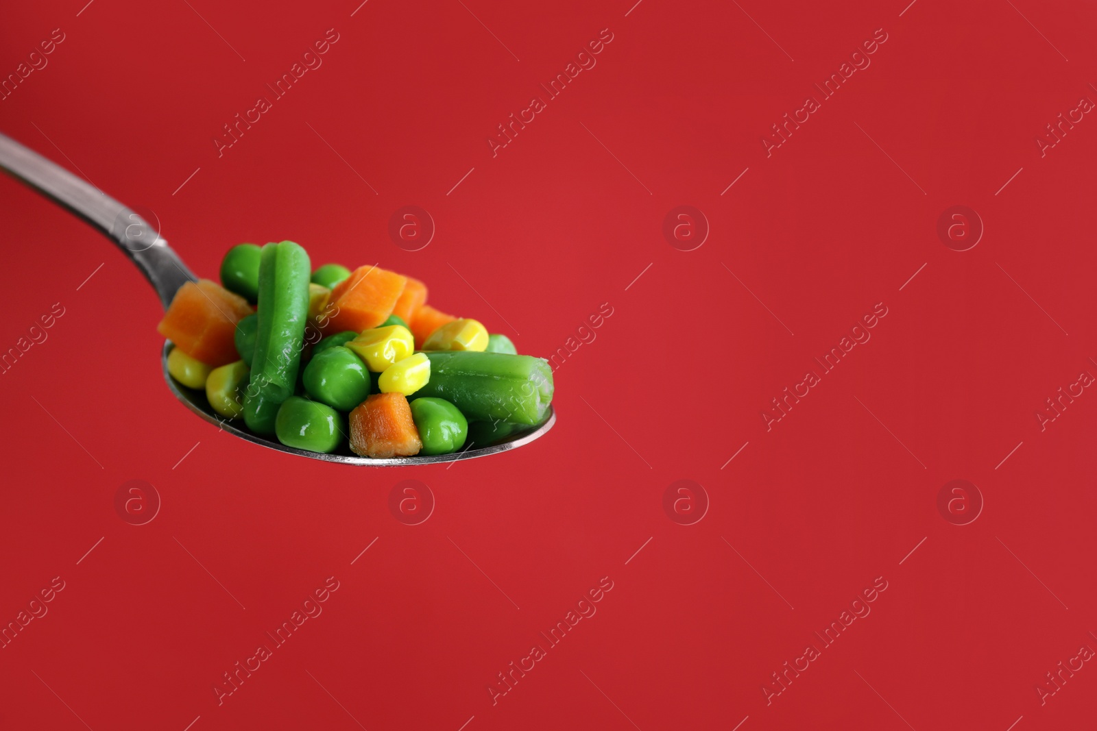 Photo of Fresh vegetables in spoon on red background. Space for text
