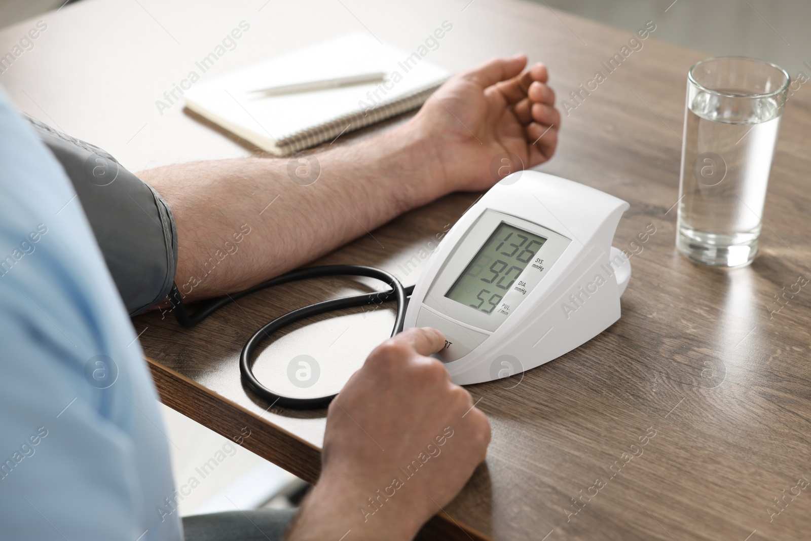 Photo of Man measuring blood pressure at table indoors, closeup