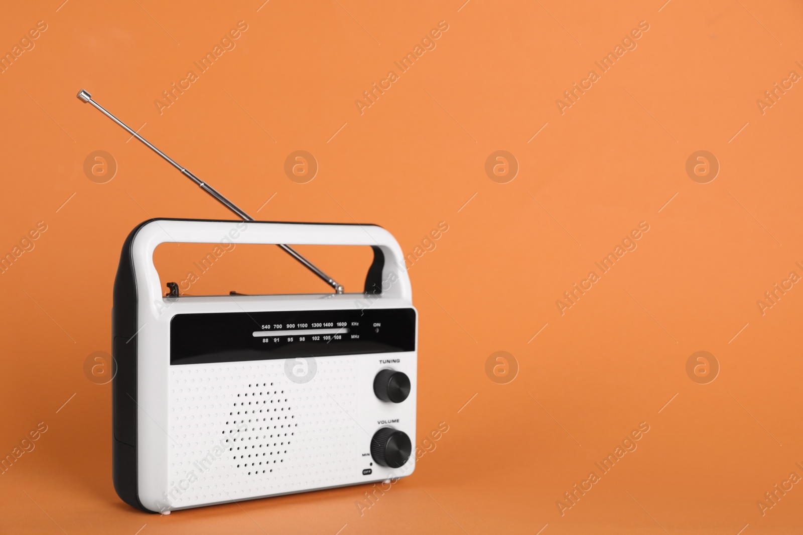 Photo of Portable retro radio receiver on orange background. Space for text