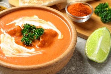 Photo of Bowl of delicious butter chicken on served table, closeup. Traditional indian Murgh Makhani