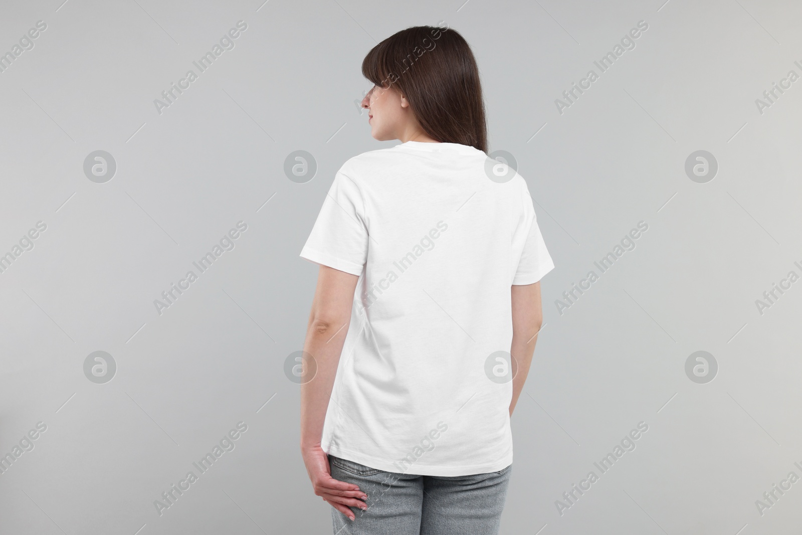 Photo of Woman in white t-shirt on grey background, back view