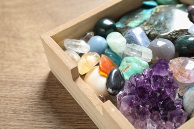 Box with different beautiful gemstones on wooden table