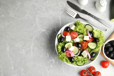 Photo of Tasty fresh Greek salad on grey marble table, flat lay. Space for text