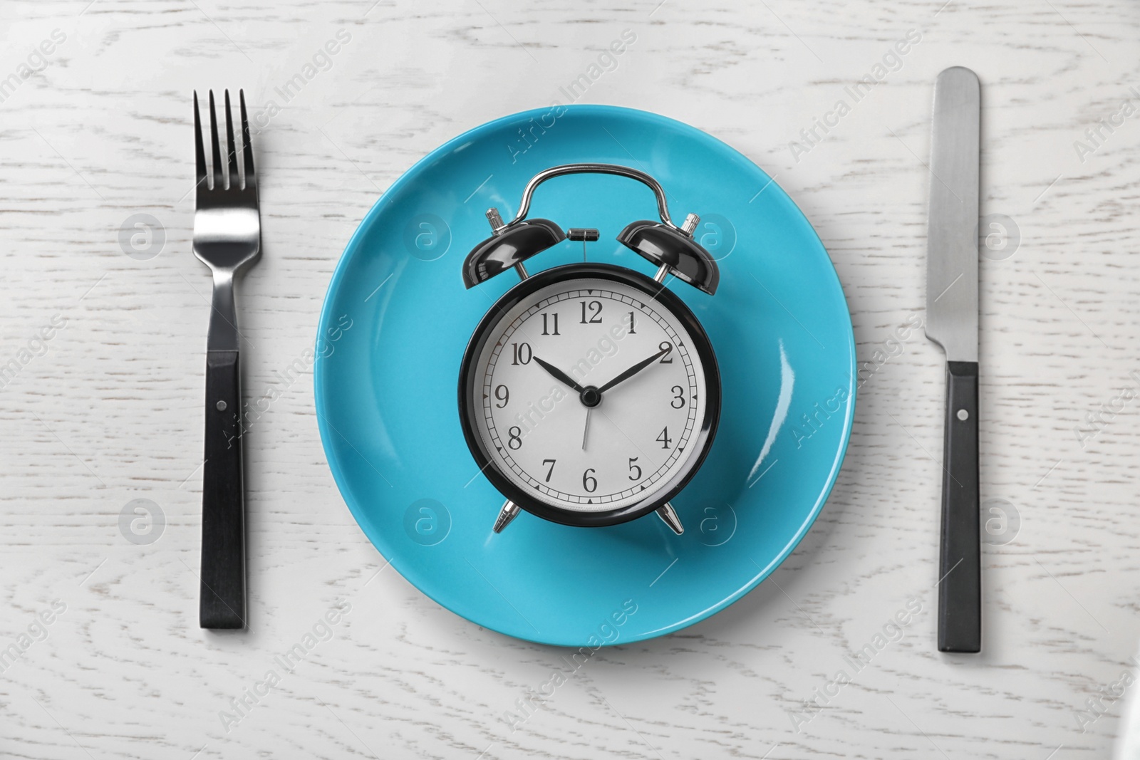 Photo of Flat lay composition with alarm clock, plate and utensils on light background