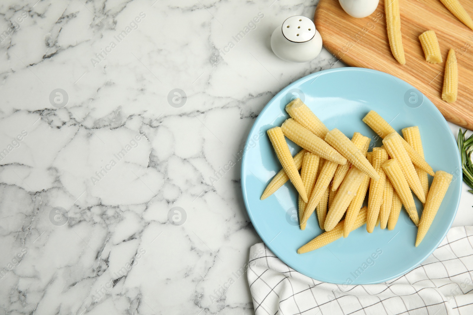 Photo of Fresh baby corn cobs on white marble table, flat lay. Space for text