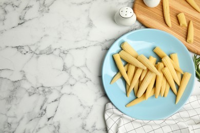 Fresh baby corn cobs on white marble table, flat lay. Space for text